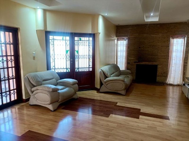 Spacious living room featuring laminate flooring, a stone feature wall with a built-in fireplace, and recessed ceiling lighting.