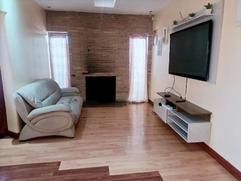 Living room featuring a stone accent wall with a fireplace, laminate flooring, and recessed lighting.