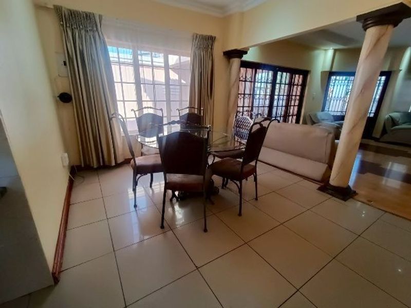 Open plan dining area featuring large tiled floors, decorative columns, and sliding glass doors leading to the exterior.