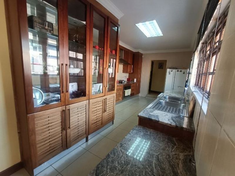 Spacious kitchen featuring extensive built-in wooden cabinetry, granite countertops, a double stainless steel sink, and functional recessed lighting.