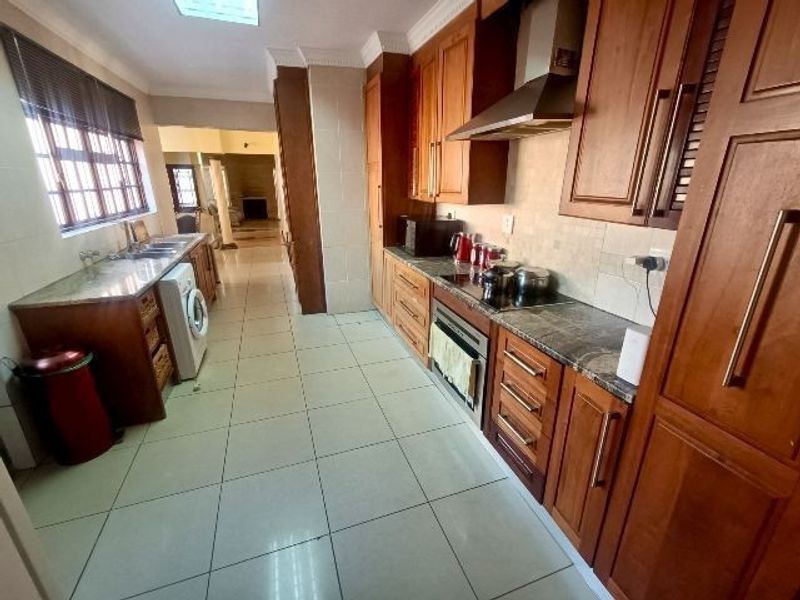 A functional kitchen featuring warm-toned wooden cabinetry, granite countertops, integrated appliances, and tiled flooring, offering a classic aesthetic with ample storage space.