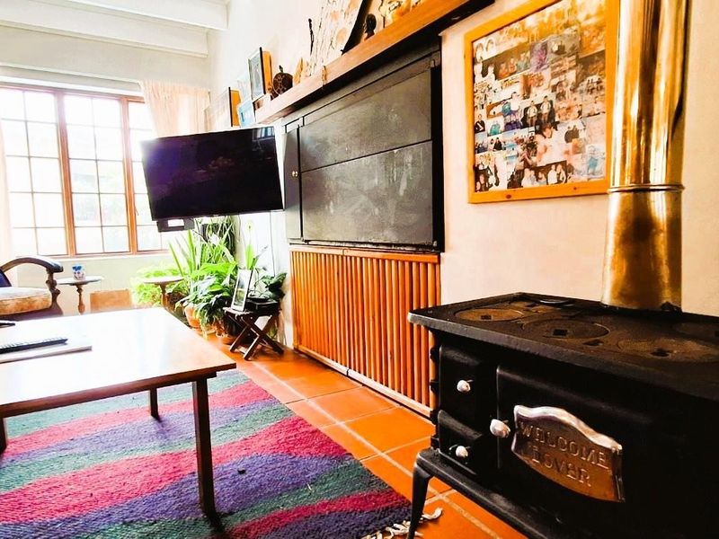 Cozy living room featuring a classic cast iron wood-burning stove, built-in fireplace, and traditional terracotta floor tiles.