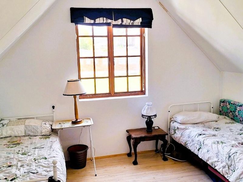 A cozy attic bedroom featuring a pitched ceiling and a timber-framed window, providing a comfortable and private sleeping space.