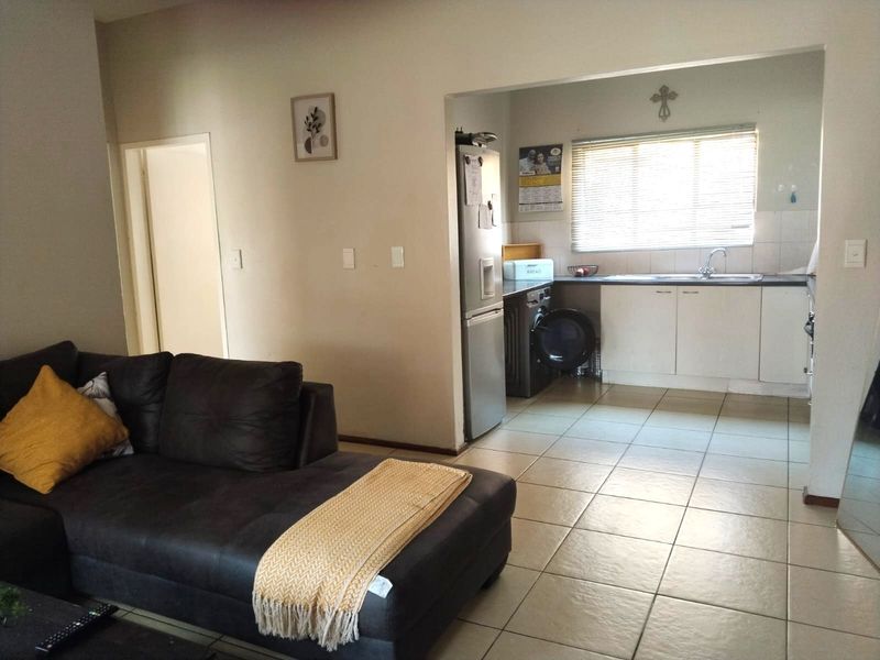 Open plan living area featuring tiled flooring and a functional kitchen with built-in cabinetry and sink.