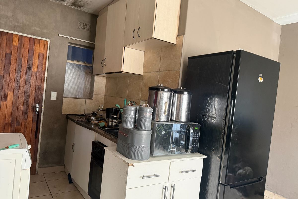 A compact kitchen featuring built-in cabinetry, a tiled backsplash, and an integrated oven, currently requiring maintenance and cosmetic updates to the ceiling and walls.