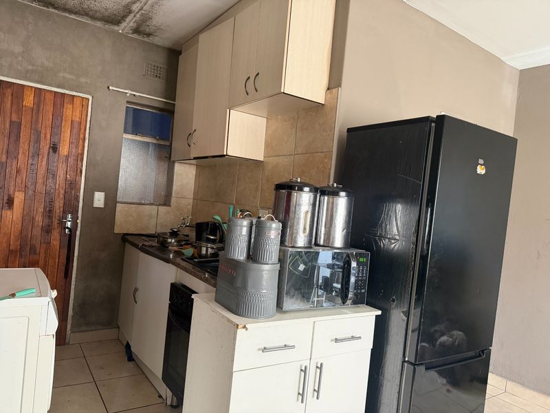 A compact kitchen featuring built-in cabinetry, a tiled backsplash, and an integrated oven, currently requiring maintenance and cosmetic updates to the ceiling and walls.