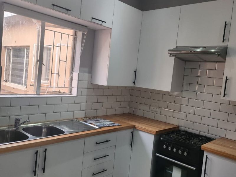 Modern kitchen featuring white cabinetry, wooden countertops, subway tile backsplash, and a gas stove with an extractor fan.