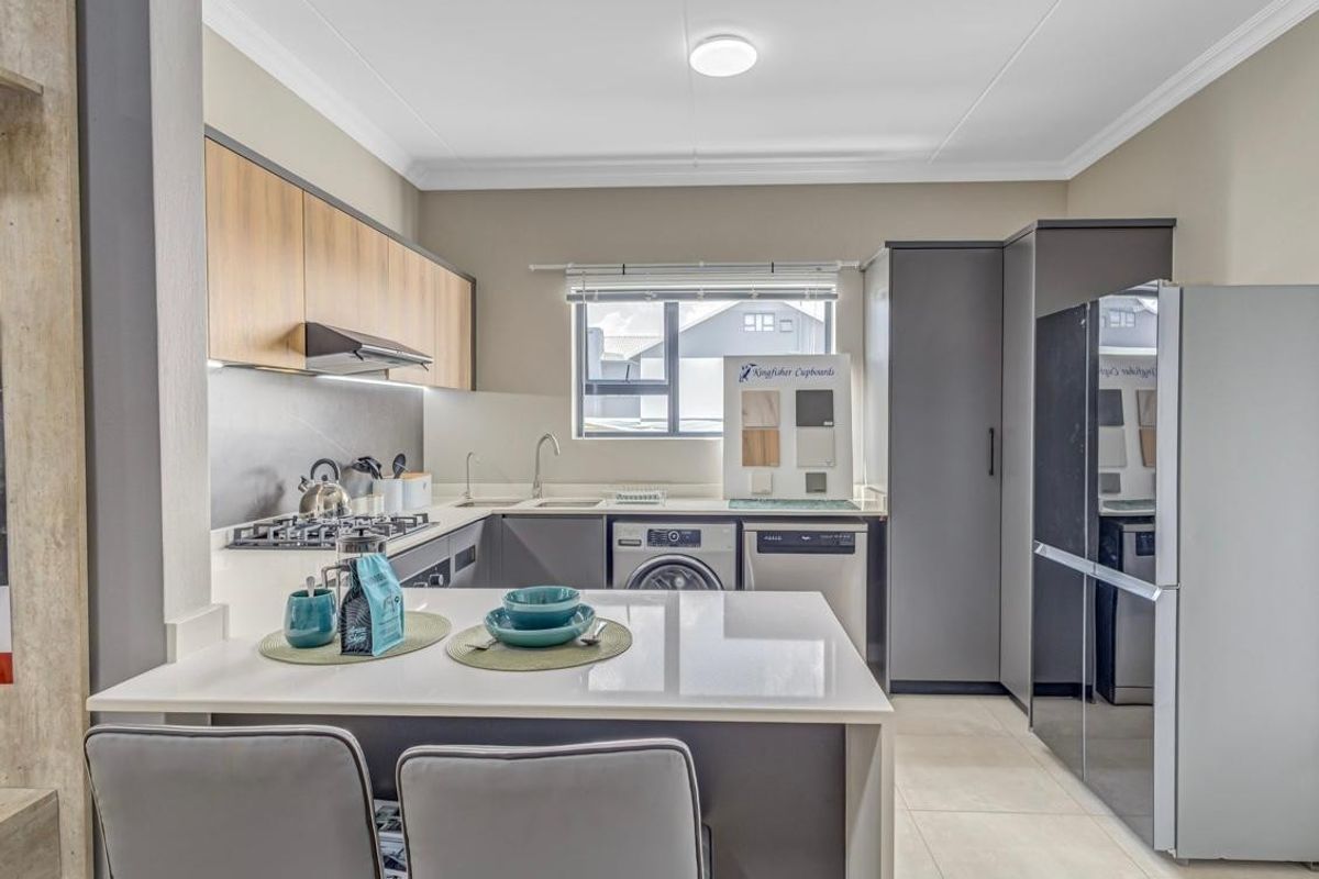 Modern kitchen featuring sleek two-tone cabinetry, quartz countertops, integrated appliances, and a functional breakfast nook, finished with contemporary tiling.