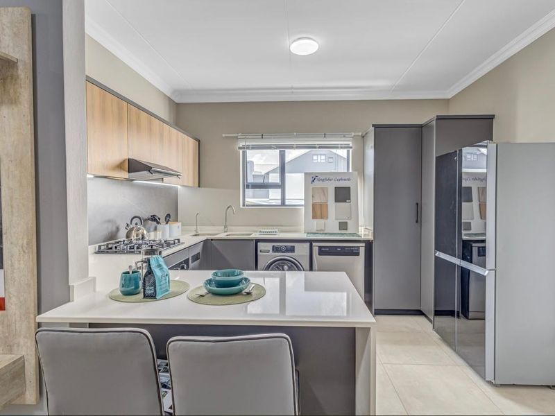 Modern kitchen featuring sleek two-tone cabinetry, quartz countertops, integrated appliances, and a functional breakfast nook, finished with contemporary tiling.