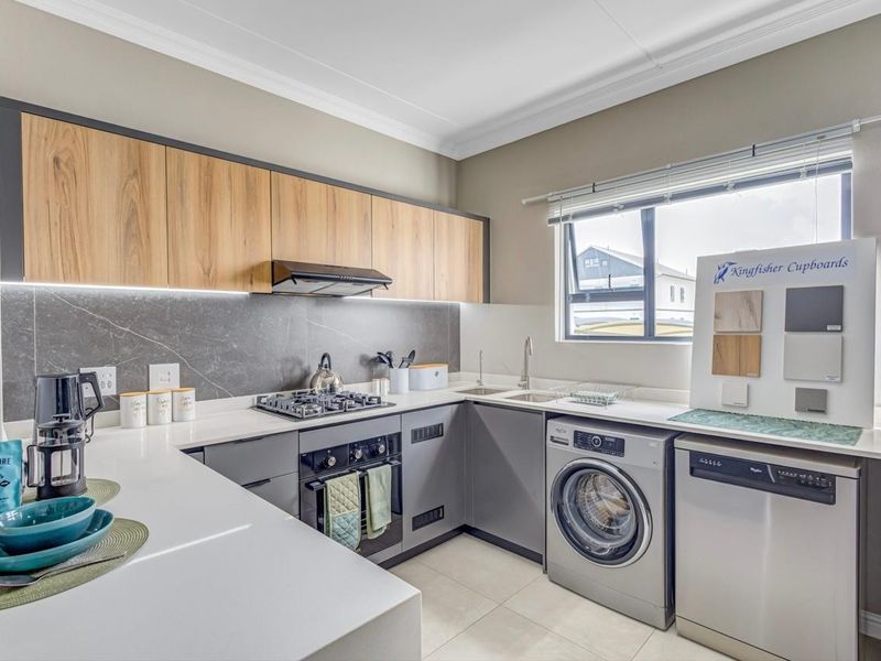 Modern kitchen featuring wood-grain and grey cabinetry, stone countertops, gas hob, built-in oven, and integrated laundry plumbing.