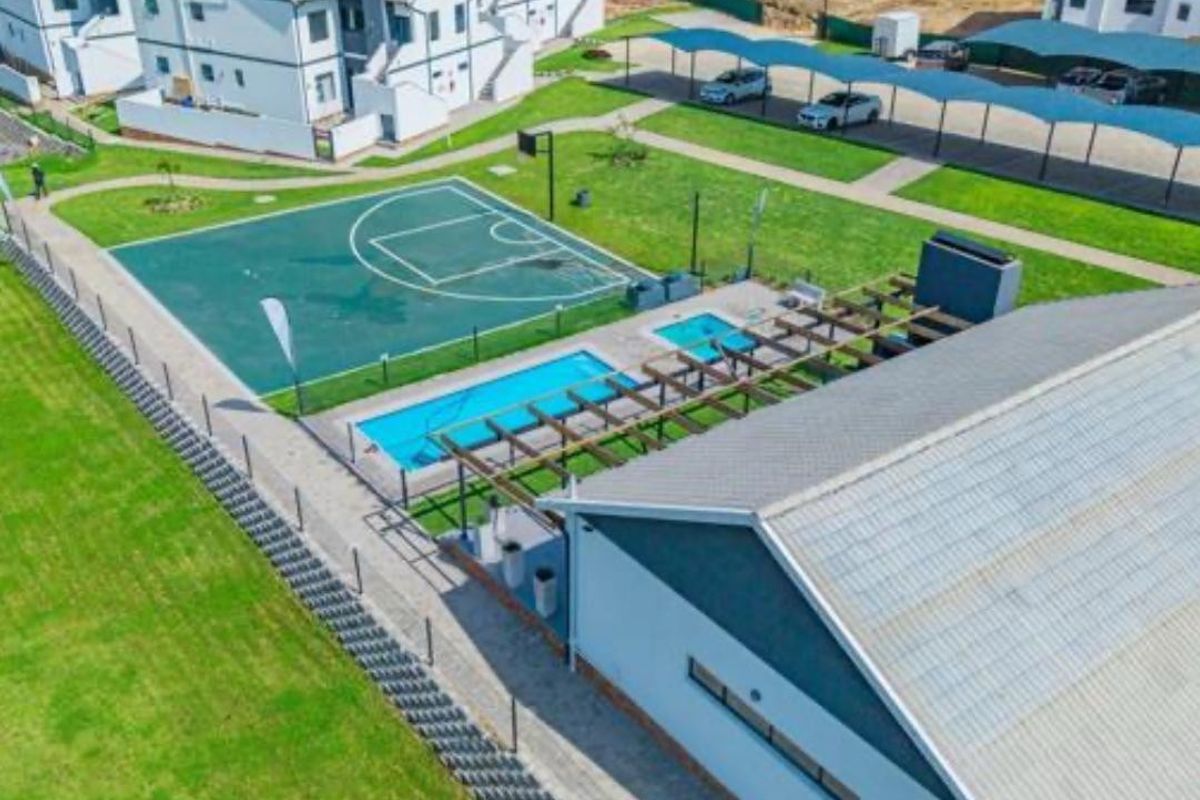 Aerial view of the apartment complex amenities, featuring a swimming pool, basketball court, pergola, and covered parking facilities.