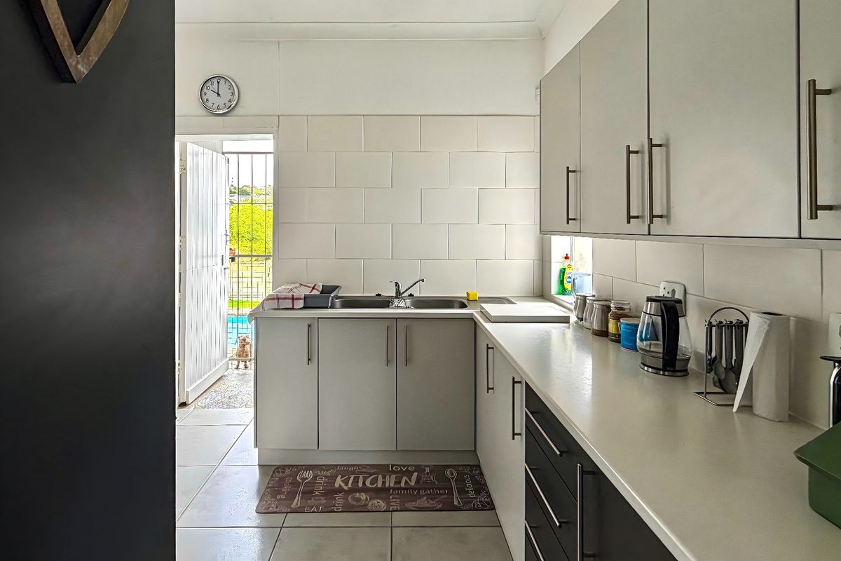 A functional kitchen featuring modern cabinetry, a stainless steel sink, tiled backsplash, and direct access to the outdoor area.