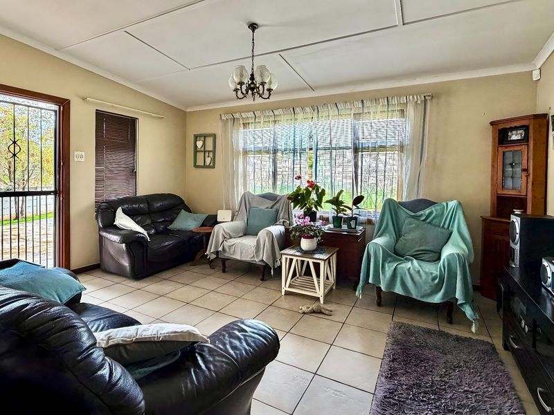 A comfortable living room featuring tiled flooring, a large window for natural light, and a decorative ceiling finish.