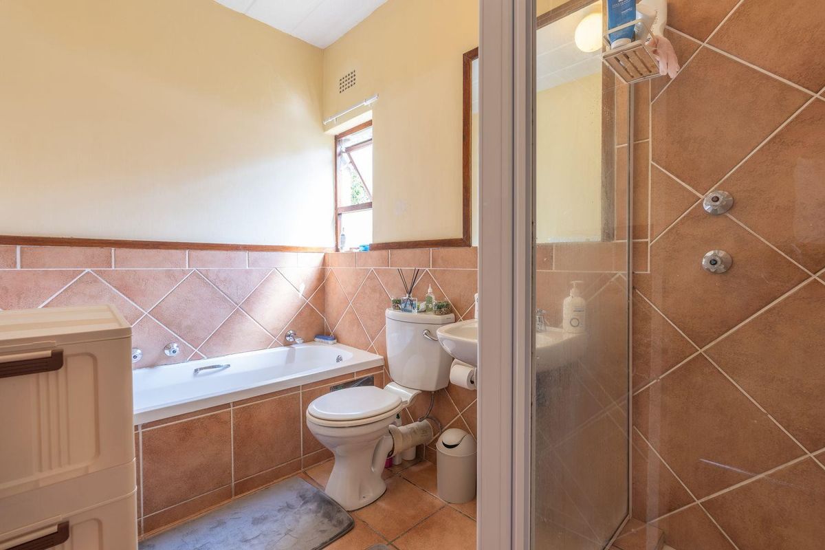 A functional bathroom featuring a bathtub, separate shower enclosure, toilet, and washbasin with classic tiled finishes.