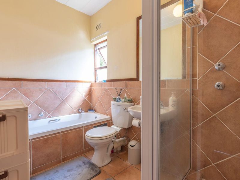A functional bathroom featuring a bathtub, separate shower enclosure, toilet, and washbasin with classic tiled finishes.