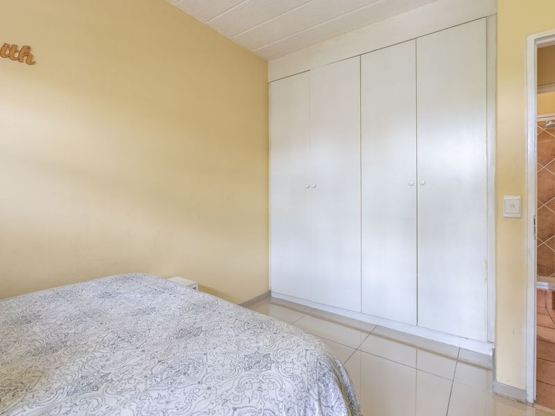 A bedroom featuring built-in cupboards, tiled flooring, and direct access to an adjoining bathroom.