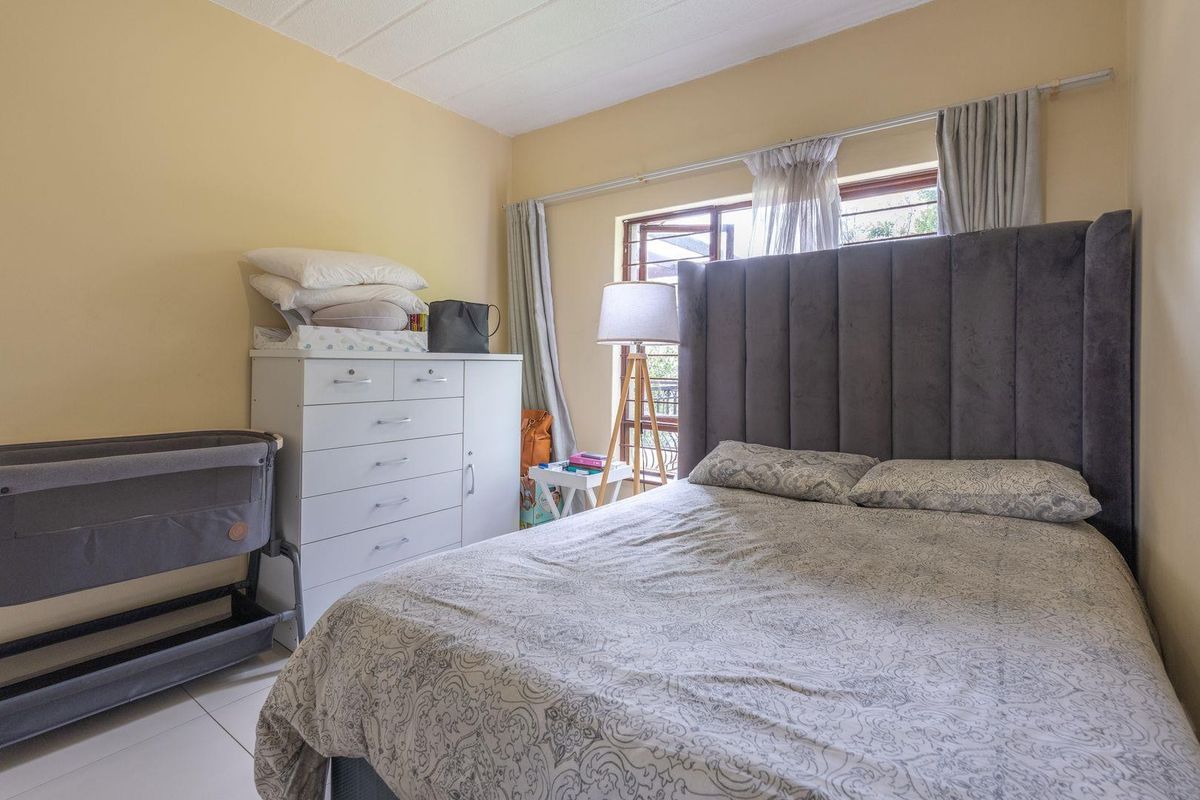 A functional bedroom featuring tiled flooring and a window fitted with security bars, providing natural light and ventilation.