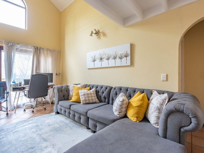 Spacious living room featuring high vaulted ceilings with exposed beams, tiled flooring, and an arched doorway leading to adjacent areas.
