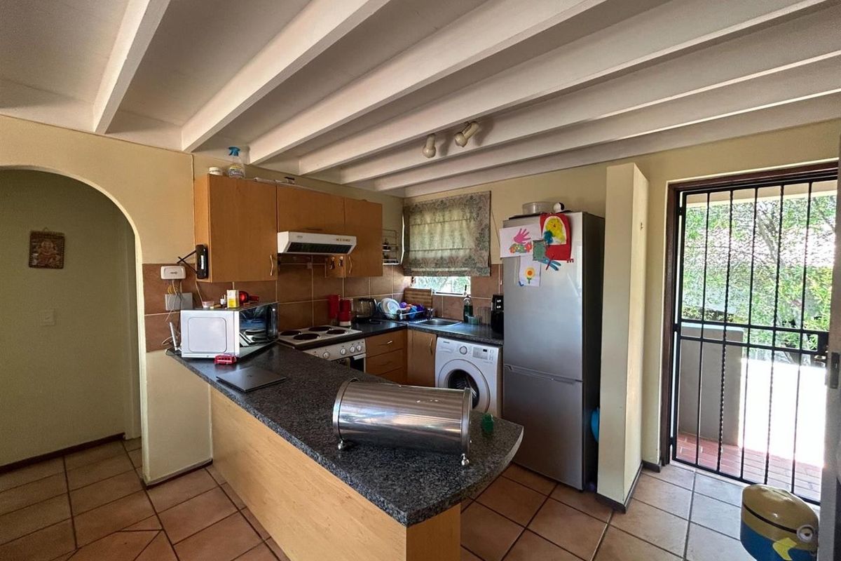 Functional kitchen featuring granite countertops, laminate cabinetry, exposed beam ceilings, and direct access to an outdoor area through a security gate.