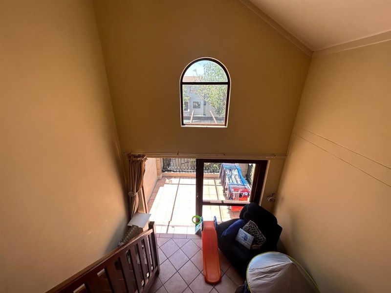 A living area featuring high ceilings, an arched window, and direct access to an outdoor balcony through a sliding glass door.