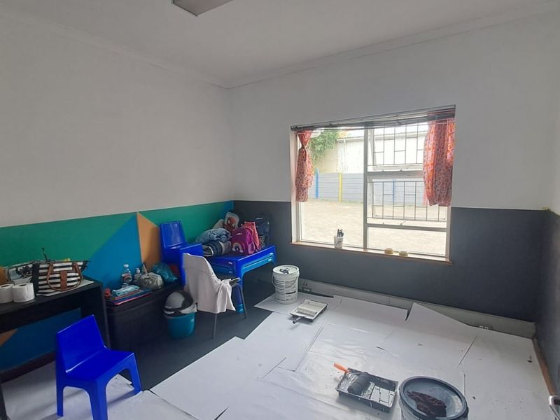 A small office space currently undergoing renovation with unfinished wall painting and aluminium window frames with security bars.