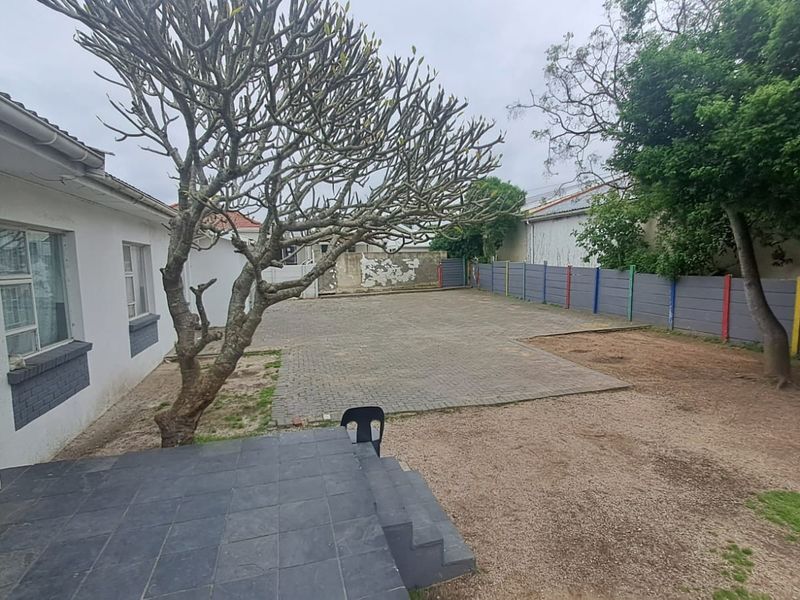 Rear exterior view of the office property featuring a paved parking area, tiled patio, and boundary walling.