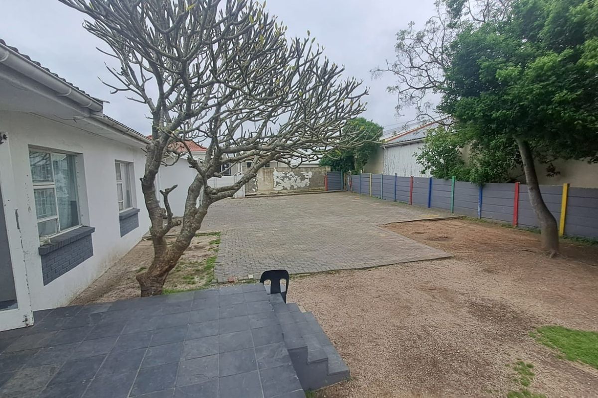 Rear exterior view of the office property featuring a paved parking area, tiled patio, and boundary walling.