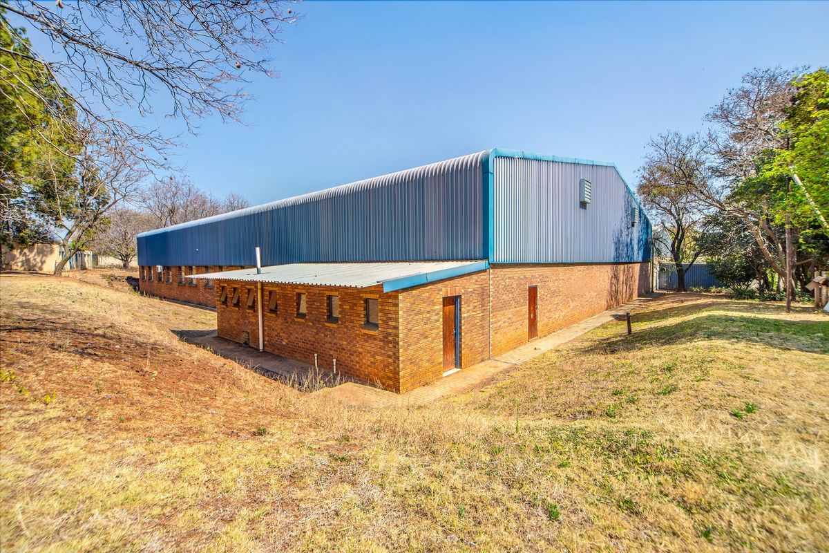 Rear view of an industrial warehouse building featuring face brick construction and a corrugated metal roof structure.