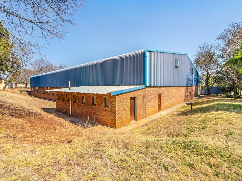 Rear view of an industrial warehouse building featuring face brick construction and a corrugated metal roof structure.