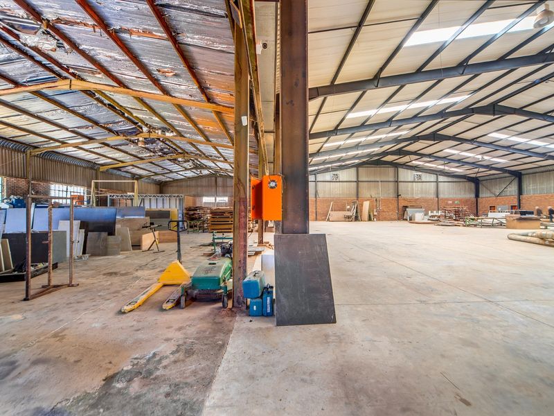 Spacious industrial warehouse featuring a steel portal frame, concrete flooring, and high ceilings with integrated skylights, suitable for various commercial or storage applications.