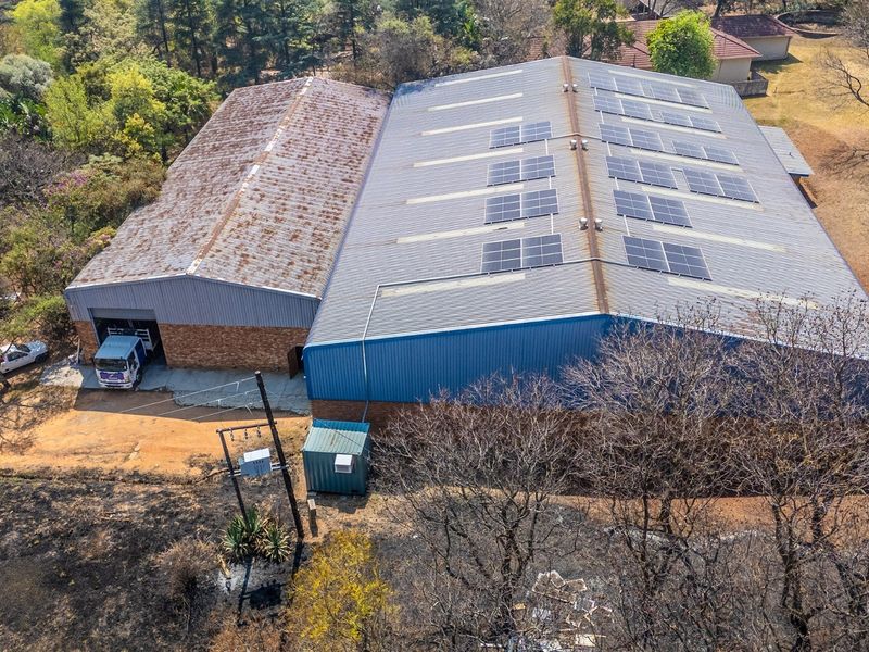 Aerial view of an industrial warehouse facility featuring a large corrugated metal roof with integrated solar panels and brick exterior walls.