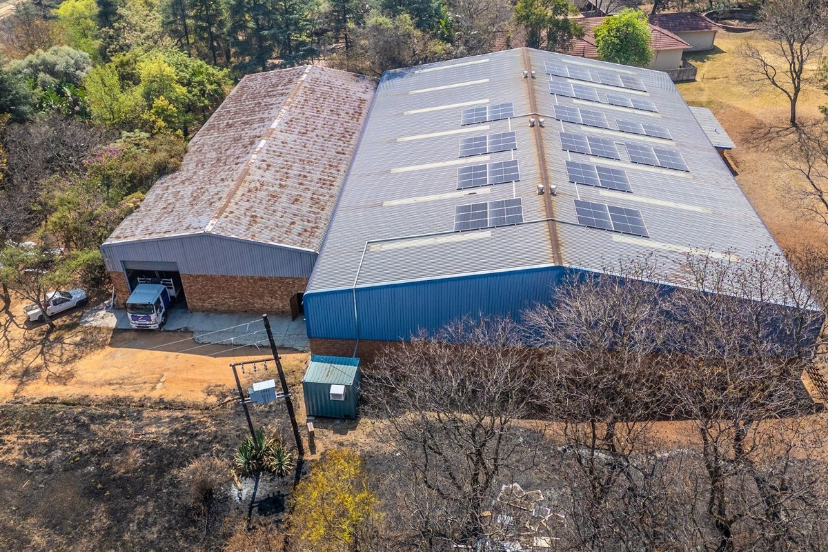 Aerial view of an industrial warehouse facility featuring a large corrugated metal roof with integrated solar panels and brick exterior walls.