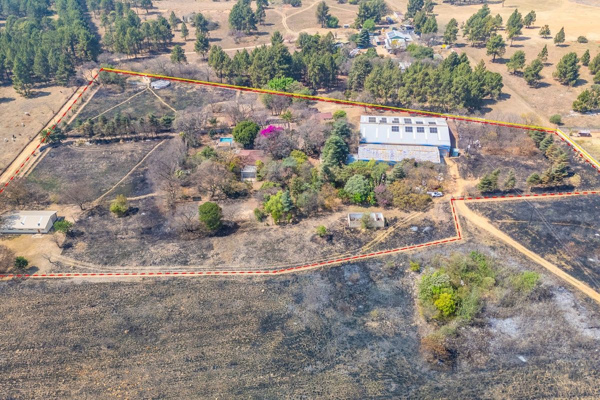 Aerial view of an industrial property featuring a large warehouse, swimming pool, and extensive grounds with marked boundary lines.