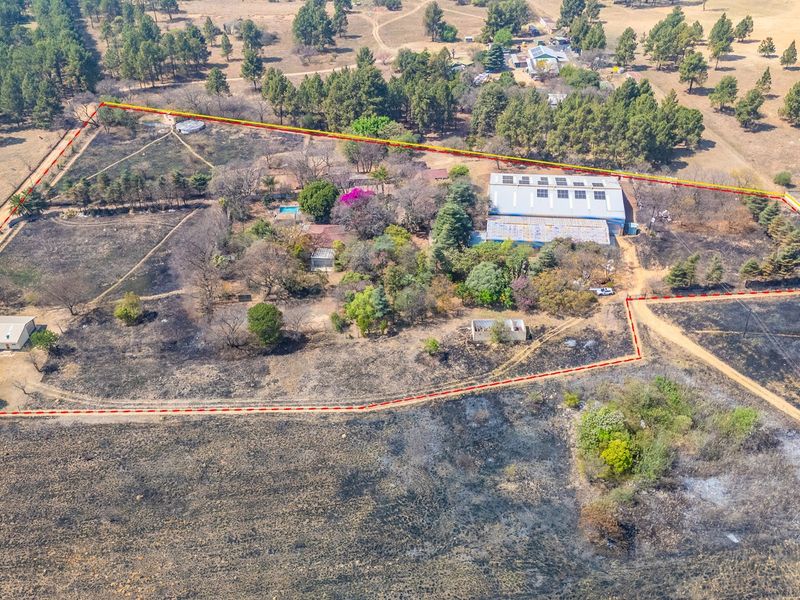 Aerial view of an industrial property featuring a large warehouse, swimming pool, and extensive grounds with marked boundary lines.