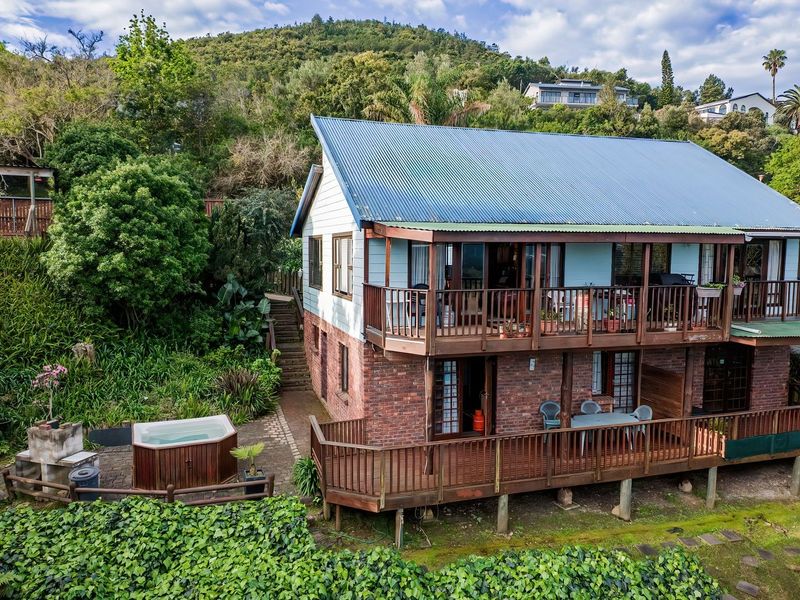 Rear view of a two-story brick and timber house featuring expansive wooden decks, a hot tub, and a built-in outdoor braai area.
