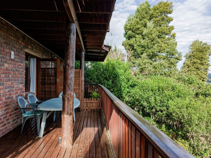 A covered timber balcony featuring exposed brickwork and a wooden balustrade, offering an elevated outdoor space with scenic views.