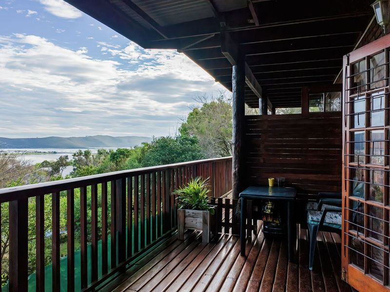 A covered timber balcony featuring a wooden balustrade and expansive views of the surrounding landscape and water.