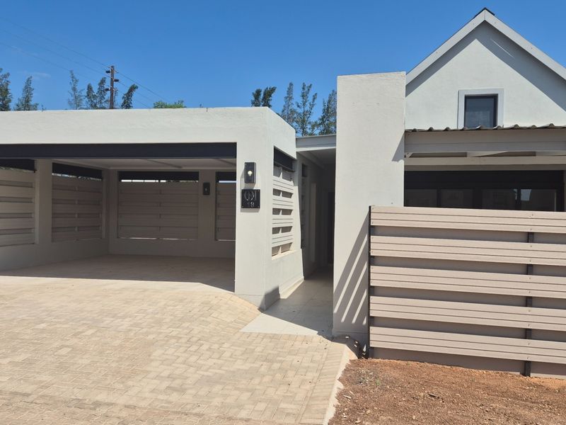 Modern front elevation featuring a double garage, paved driveway, and contemporary timber slat fencing with clean architectural lines.
