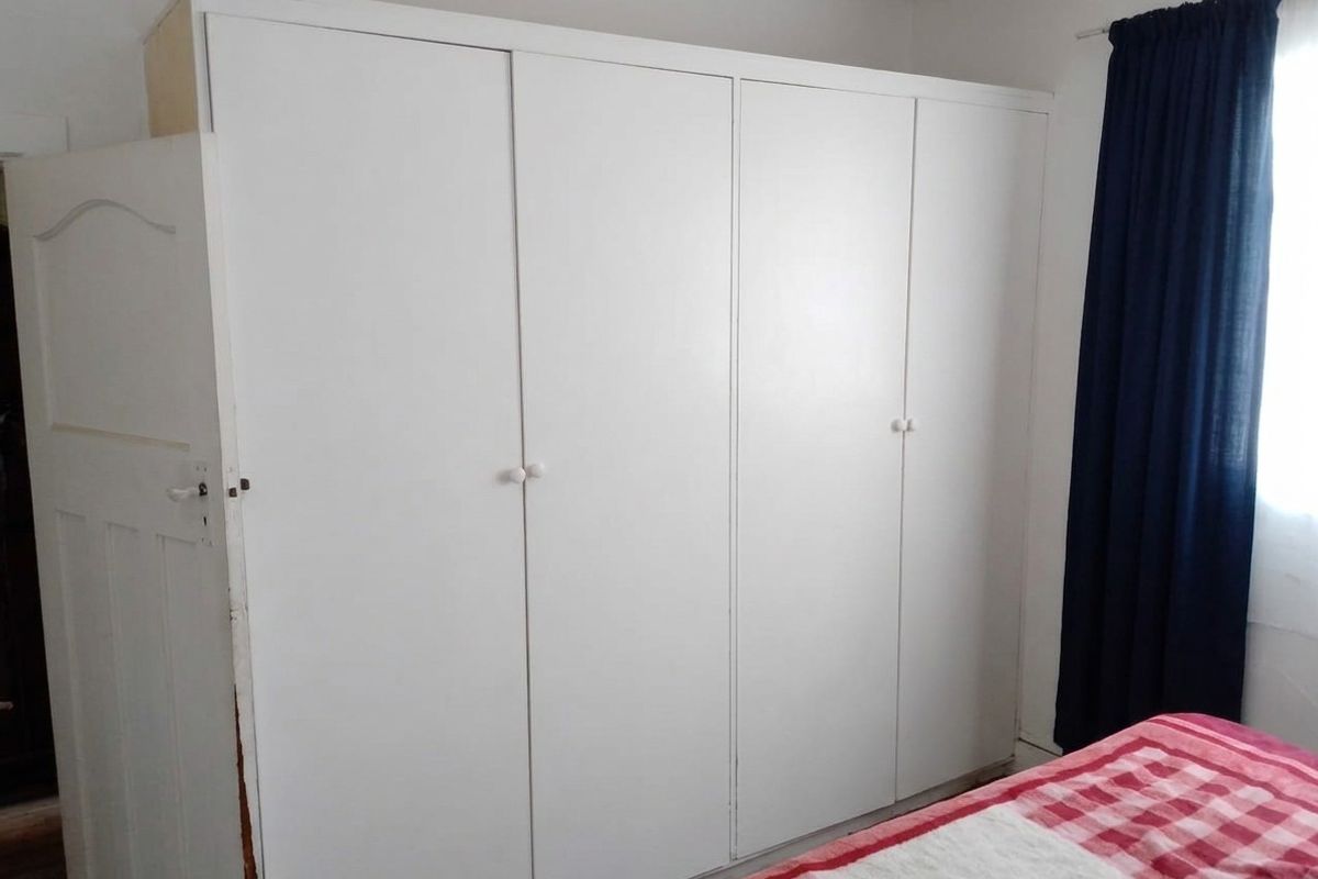 A bedroom featuring a large white built-in wardrobe with four doors, providing ample storage space.