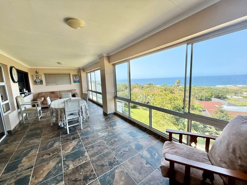 Enclosed patio area featuring large sliding windows with expansive ocean and garden views, finished with durable floor tiles.