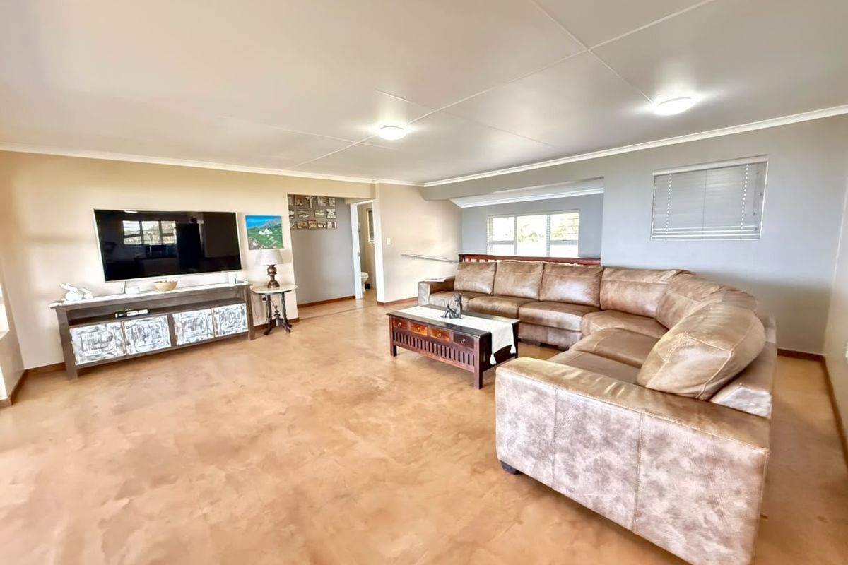 Spacious living room featuring polished concrete flooring, neutral wall tones, and natural light through fitted window blinds.