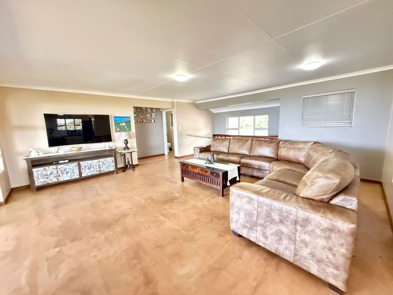 Spacious living room featuring polished concrete flooring, neutral wall tones, and natural light through fitted window blinds.