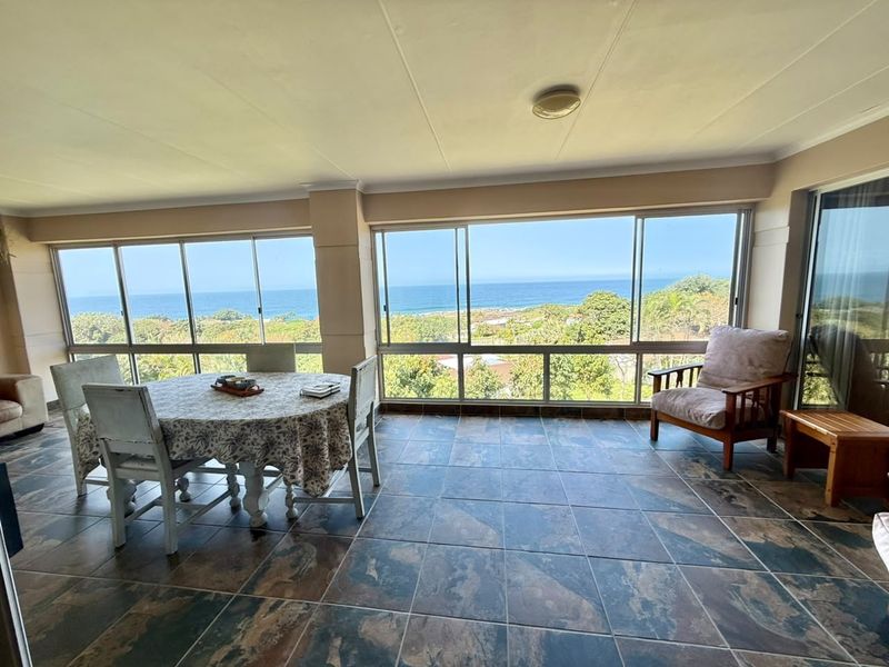 Enclosed patio area featuring large sliding windows with expansive ocean and coastal views, finished with durable floor tiles.