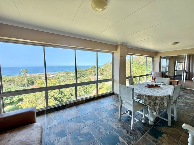 Enclosed patio area featuring extensive glass windows with panoramic ocean views and durable tiled flooring, offering a bright and versatile living space.