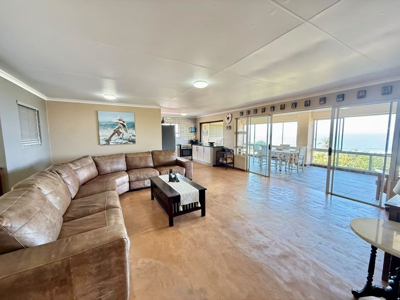 Spacious open-plan living area featuring a kitchen, dining space, and seamless access to a covered patio with ocean views.
