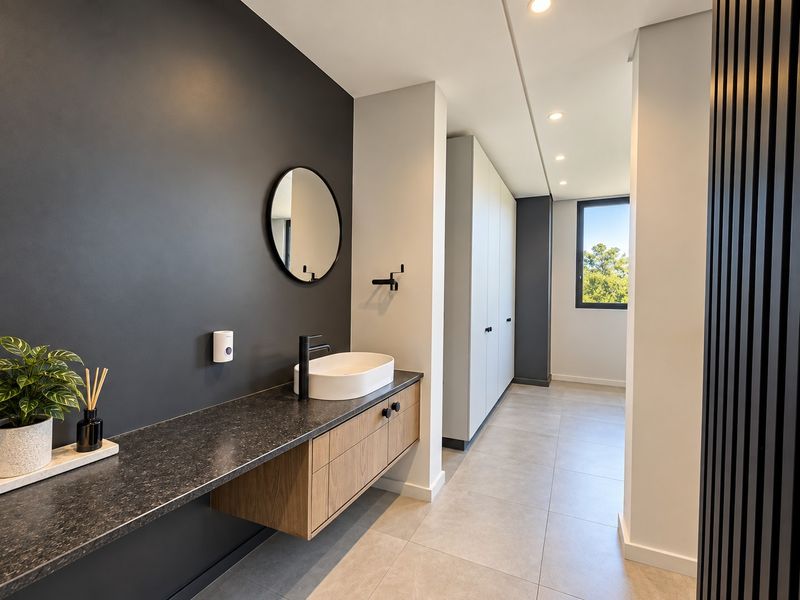 Modern bathroom featuring a floating vanity with a vessel sink, sleek black fixtures, and ample built-in storage cabinetry.