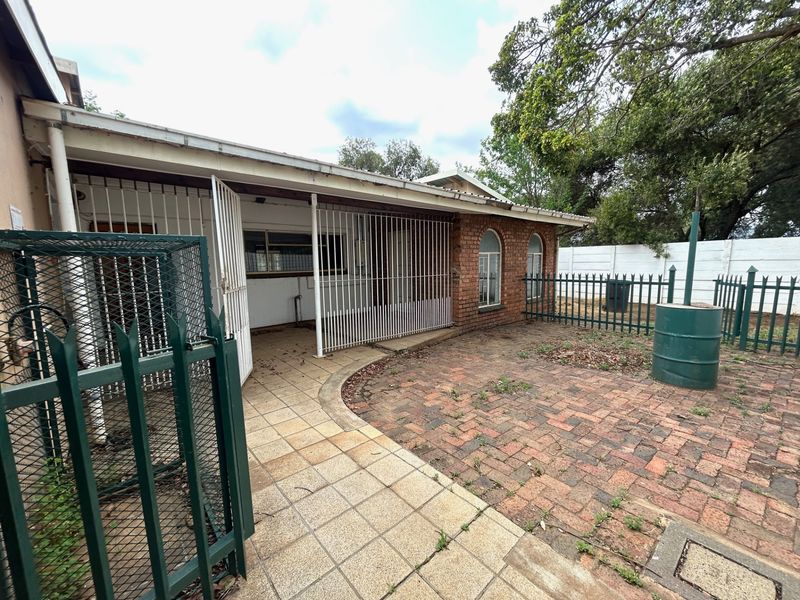 Rear exterior view of the farm property featuring a paved patio area, security gates, and brick facade with arched windows.