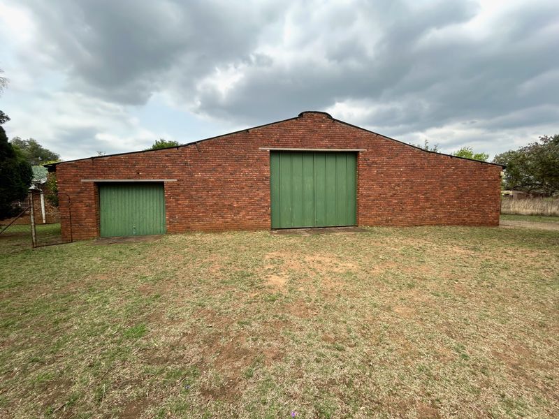 A large brick farm outbuilding featuring a prominent sliding barn door and an integrated garage door, set against a grassy yard.