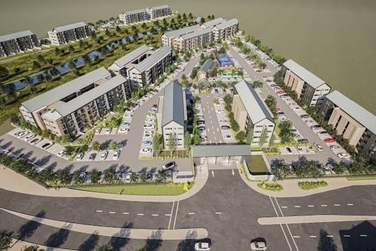 Aerial view of a modern residential apartment complex featuring multiple building blocks, paved parking, and landscaped communal areas.