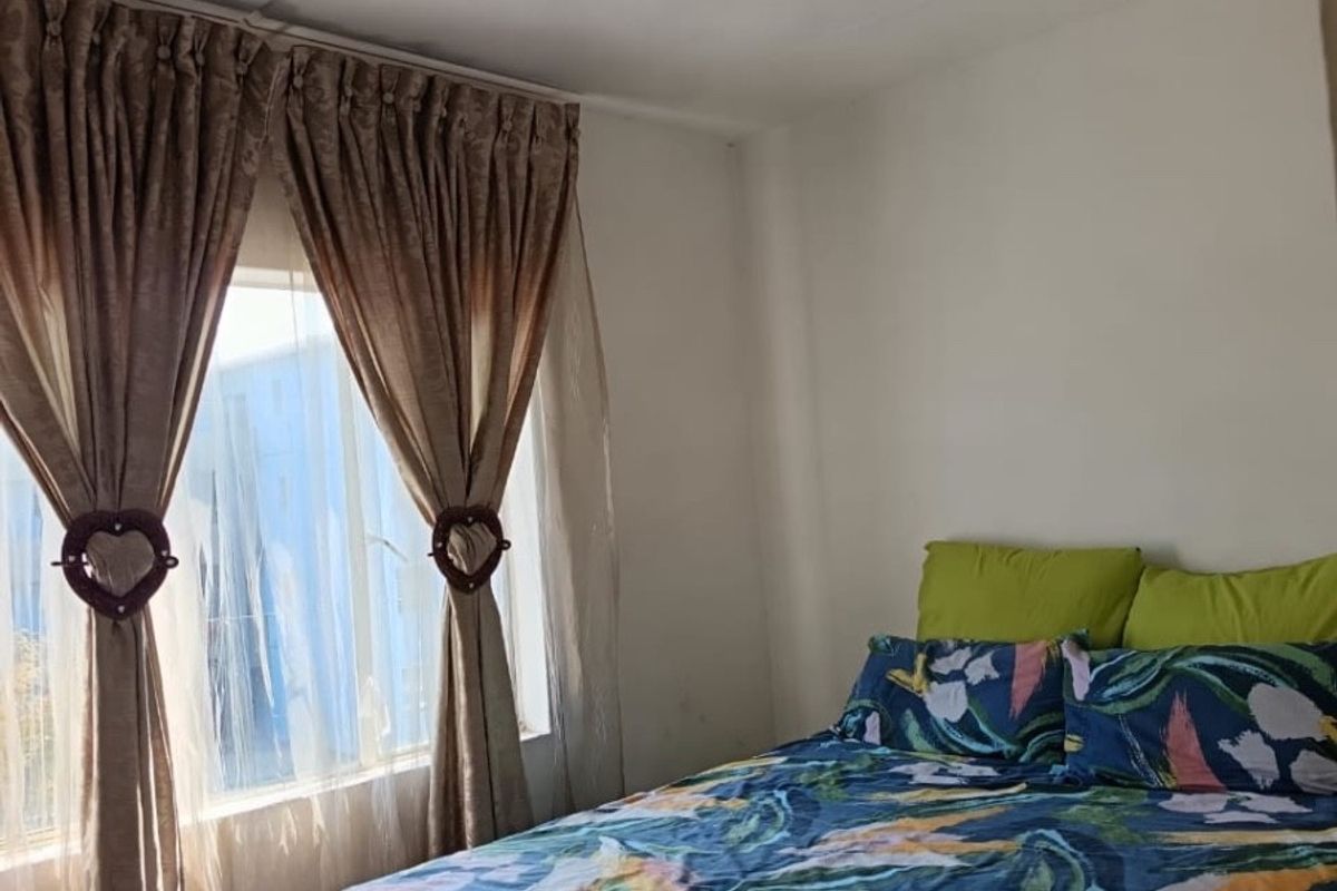 A standard bedroom featuring a window with curtains and a central ceiling light fixture.